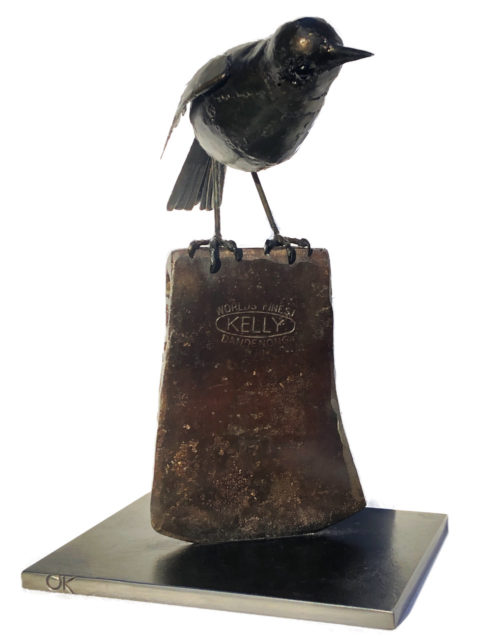 Steel sculpture of a blackbird perched on an axe head. By Tony O'Keefe. Artist from Queenstown, New Zealand.